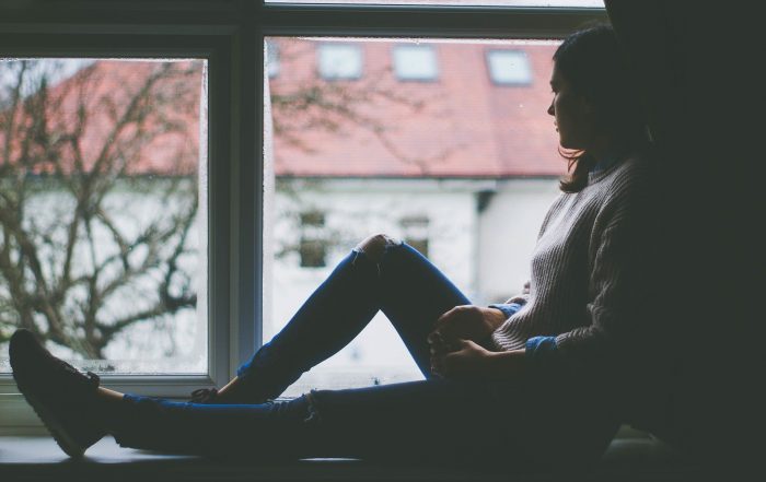 woman sat by window, winter, seasonal affective disorder