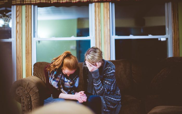 two grieving women on sofa